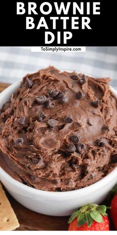 chocolate brownie batter dip in a white bowl with strawberries and crackers on the side