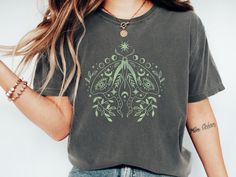 Embrace the celestial charm with our Moth Shirt, featuring a mystical moon phase design on a Cottagecore-inspired Comfort Colors® tee. This boho flower tee combines vintage vibes with a dreamy aesthetic, perfect for adding a touch of magic to your wardrobe. Welcome to OVERRJOY! * Q U I C K * F A C T S * ✺ 100% preshrunk cotton ✺ Wash and dry normally (on cool for best results) * S I Z I N G * ✺ Sizing is relaxed fit - Comfort Colors. ✺ Most women find their typical size works best, since they ar Bohemian Short Sleeve Tops With Moon Print, Bohemian Tops With Moon Print Relaxed Fit, Casual Moon Print Tops For Festival, Cottagecore Aesthetic, Comfort Colors Tee, Moon Phases, College Outfits, Vintage Tees, Comfort Colors