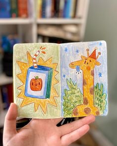 a hand holding an open children's book with pictures of animals and pumpkins