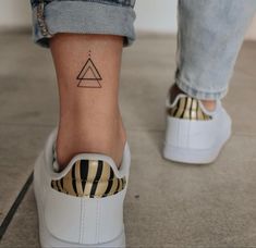 a woman's foot with a small triangle tattoo on it