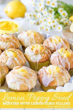 lemon muffins with icing on a white plate next to flowers and lemons