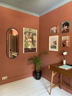 a room with pink walls and pictures on the wall, including a plant in a black vase