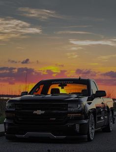 the truck is parked on the side of the road in front of the setting sun