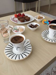 two cups of coffee sit on the table with desserts