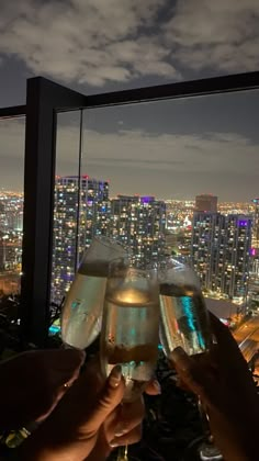 two people toasting with wine glasses in front of a cityscape at night