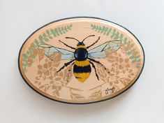 a wooden plate with a bee painted on it