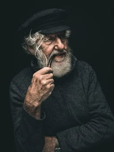 an old man with a long beard is holding a pipe in his hand and looking at the camera