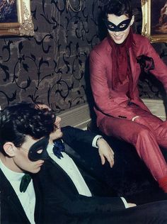 two men in tuxedos sitting next to each other with masks on their faces