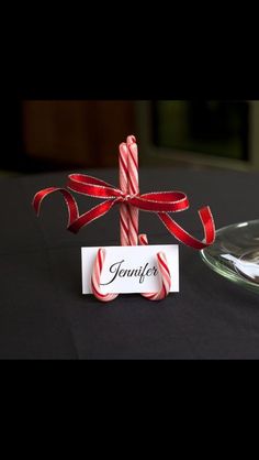 two candy canes tied to a table with a name tag on it and a glass plate