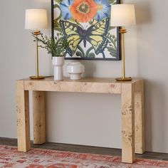 a wooden table with two lamps and a painting on the wall