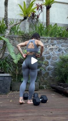 a woman standing on top of a wooden floor next to two black dumbbells