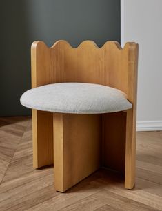 a wooden bench with a white cushion on the seat and wood flooring in front of it