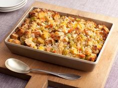 a casserole dish on a cutting board with spoons and plates in the background