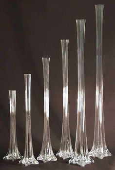 four tall glass vases sitting next to each other