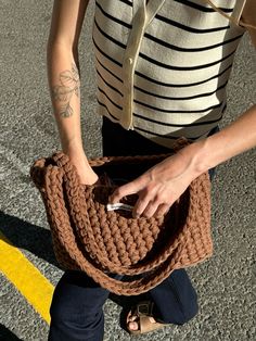 a woman holding a brown purse on top of a parking lot next to a yellow line