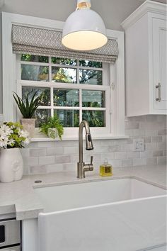 a white kitchen sink sitting under a window next to a potted plant on top of a counter