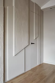 an empty room with wooden floors and white walls, along with three panels on the wall