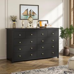 a black dresser with lots of drawers and pictures on the wall above it in a living room