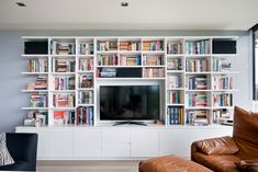 a living room filled with furniture and a flat screen tv sitting on top of a book shelf