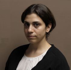 a woman is standing in front of a wall with her head turned to the side