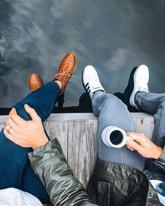 two people sitting next to each other on a dock with their feet up in the air