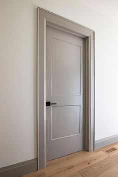 an empty room with a closed door and hard wood flooring