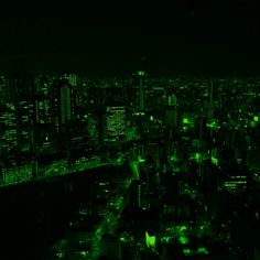 an aerial view of a city at night with green lights and buildings in the background