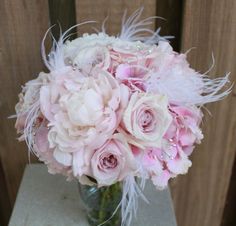 a vase filled with pink flowers and feathers