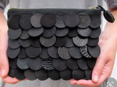 a person holding a black purse with lots of buttons on it