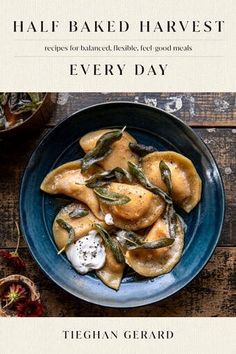 a blue plate topped with ravioli next to two bowls filled with sauce and herbs