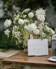 a bouquet of white flowers sitting on top of a wooden table