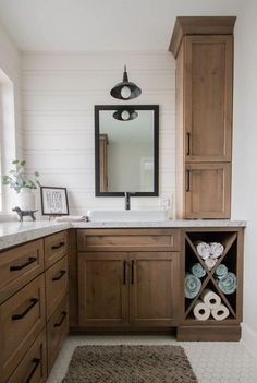 a bathroom with wooden cabinets and white walls