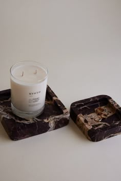 two marbled trays with a candle on one that is sitting next to each other