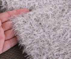 a person's hand is touching the fur on a blanket