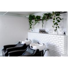 a row of black chairs sitting next to each other in front of a white tiled wall