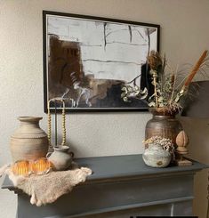 two vases sitting on top of a mantle next to a painting and other items