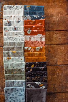 six different colors of fabric hanging on a wooden wall, each with flowers and leaves