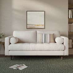 a white couch sitting on top of a carpeted floor next to a book shelf