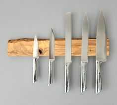 five knives are hanging on a wall with a piece of wood attached to it's side