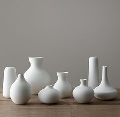 several white vases sitting on top of a wooden table