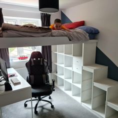 two children are sleeping on top of bunk beds in the same room, one boy is sitting at his desk