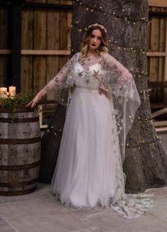 a woman standing next to a tree wearing a white dress