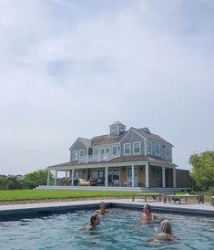 some people are in the water near a large house