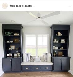 a living room with built in bookshelves and a window seat on the far wall