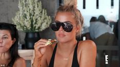 two beautiful women sitting at a table with food in front of their faces and one woman wearing sunglasses