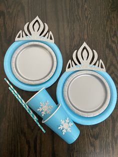 two plates and cups are sitting on a table with paper straws in the shape of snowflakes