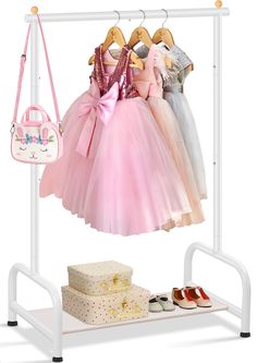 a white rack with pink dresses and shoes hanging on it's sides next to a purse