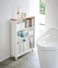 a bathroom with a toilet, book shelf and bathtub in the corner next to it