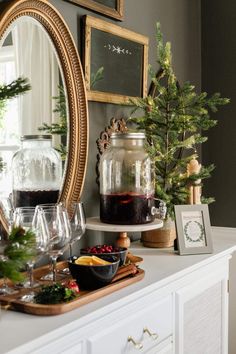 a table topped with wine glasses next to a mirror and christmas decorations on top of it