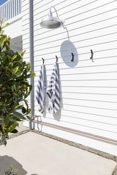 three towels hanging on the side of a white house next to a potted plant